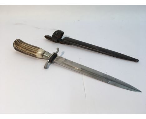 A WW1 German fighting knife with horn handle, a bright blade, a black painted scabbard and leather strap.