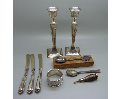 A pair of silver candlesticks, a silver napkin ring, two silver spoons, a metal and horn scent bottle and three knives, weigh