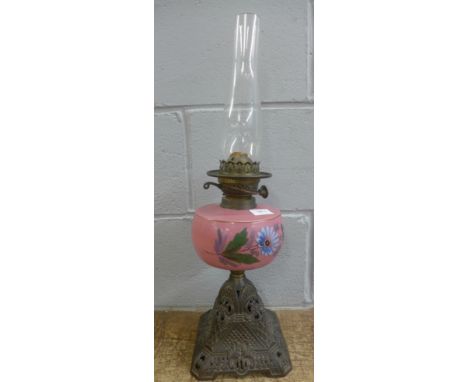 An oil lamp with a floral decorated reservoir and cast metal base 