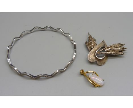 A textured silver bangle, a silver and opal pendant and a silver brooch 