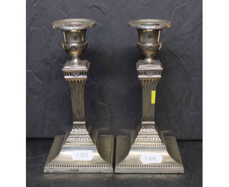 A pair of late Victorian silver pillar candlesticks of reeded column design on square bases, hallmarked for Sheffield 1900, 1