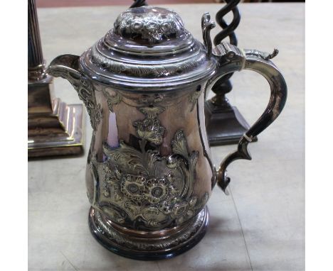 A 17th Century style lidded silver plated jug with mask spout, 9" high together with a pair of spiral twist brass candlestick