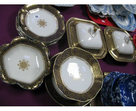 An Ashworth Ironstone Part Dinner Service, in cream with gilt and blue border, comprising two lidded tureens, comport, fluted