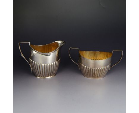 Edwardian silver milk jug, of oval part fluted form, hallmarked Atkin Brothers, Sheffield 1901, together with a similar twin 