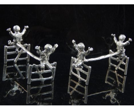 A pair of silver knife rests, S. J. Rose & Son, Birmingham 1969, fashioned as boys sitting on a gate. W. 9.5cm