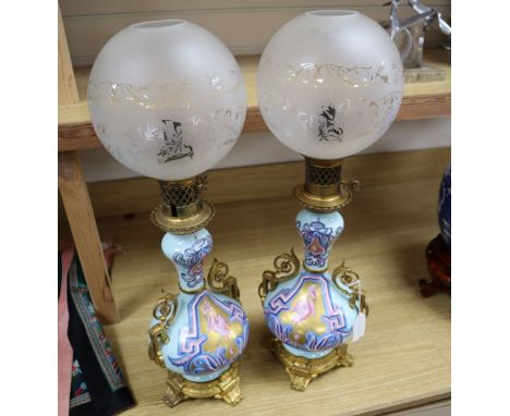 A pair of Napoleon III Paris porcelain ormulu mounted oil lamps, complete with clear glass etched shades, 63cm total height
