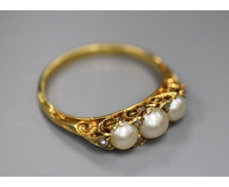 An early 20th century yellow metal and three stone split pearl set half hoop ring, with diamond chip spacers, size P, gross 3