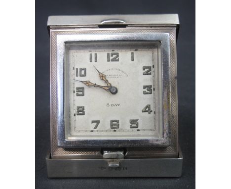 GEORGE V SILVER TRAVEL CLOCK, the folding case with engine turned decoration, the eight day clock face marked: Goldsmiths and