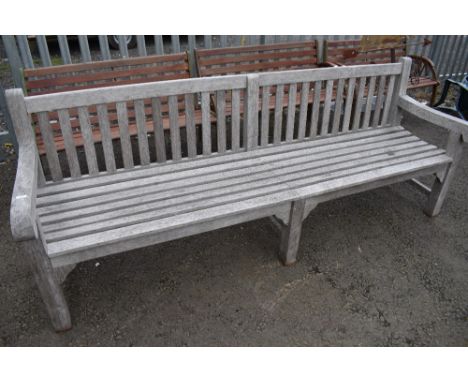 A traditional teak garden bench of very long proportions (one of two) length approx 240cm