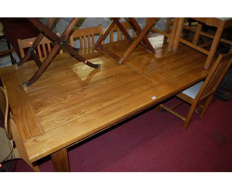 A contemporary light elm extending dining table, having pull-out action and two extra drop-in leaves, on square tapering supp