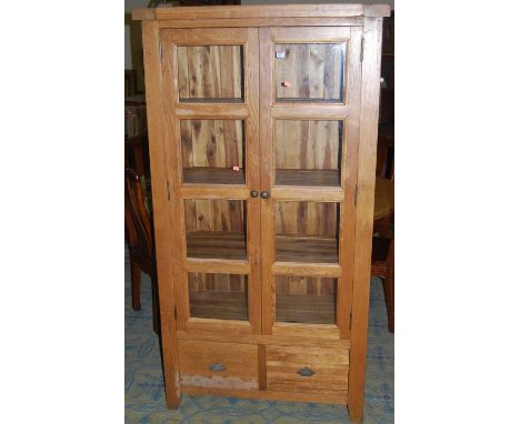 A contemporary light oak double door glazed display cabinet, having twin short lower drawers, w.97.5cm 