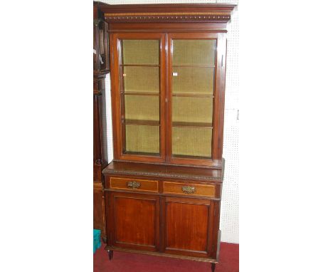 A circa 1900 mahogany bookcase cupboard, having twin glazed upper doors over base fitted with twin frieze drawers above confo