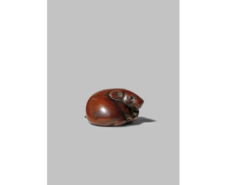 A JAPANESE WOOD NETSUKE OF A RAT EDO/MEIJI PERIOD The chubby rodent depicted lying and tenderly clutching a large bean pod, t