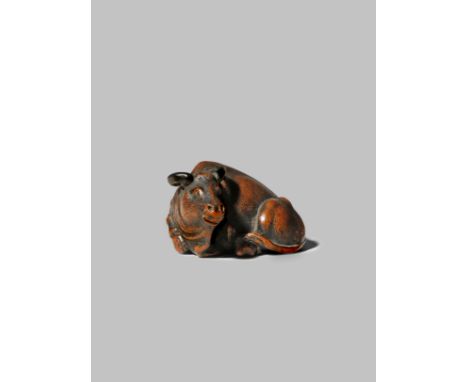 A JAPANESE WOOD NETSUKE EDO/MEIJI PERIOD Depicting a large ox reclining, its legs neatly tucked underneath the body, its horn