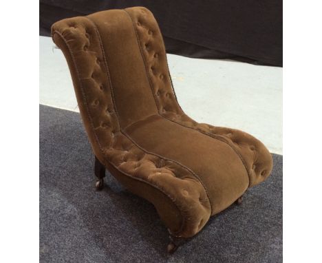 A Victorian nursing chair of scroll form with button down upholstery above turned rosewood front legs with applied castors.