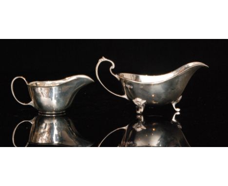 A mid 20th Century hallmarked silver sauce boat of plain form with reeded rim and foliate capped scroll feet, Sheffield 1961,