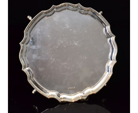 A hallmarked silver salver of plain circular form with pie crust border on four pad feet, diameter 25cm, weight 15oz, Sheffie