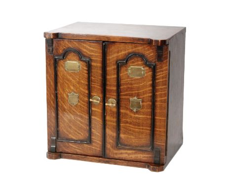 A late 19th Century oak smokers cabinet in the form of a safe, fitted with a pipe rack and brass cigar cutter surrounded by t