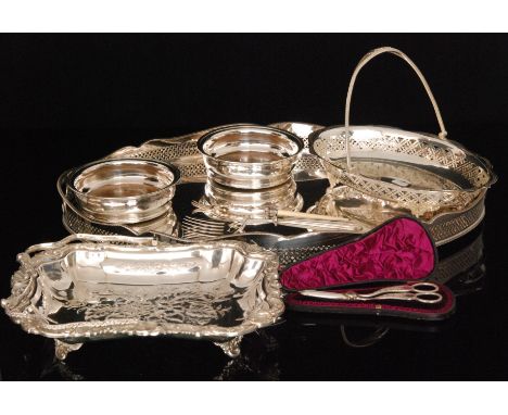 A quantity of silver plated items to include a cased set of grape scissors, an oval pierced swing handled basket, another of 