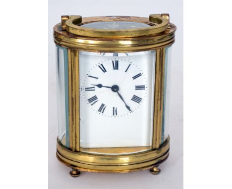 An early 20th Century oval French brass carriage clock the enamelled Arabic dial enclosed by glass panelled sides on cone fee