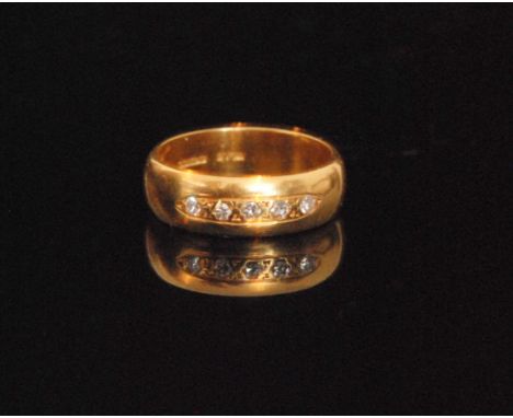 A 18ct hallmarked wedding ring detailed with five claw set brilliant cut diamonds, ring size L.