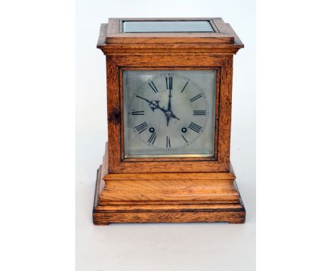 A late 19th Century oak cased mantle clock the square silvered dial with eight day striking movement on two gongs enclosed by