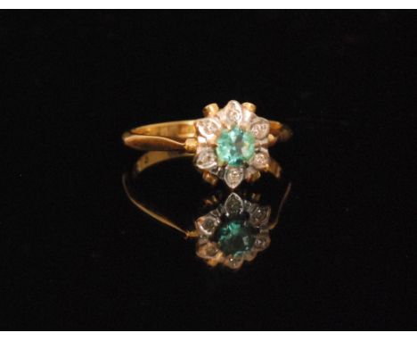 An 18ct emerald and diamond cluster ring, central emerald within a six stone diamond surround to knife edged shoulders, ring 