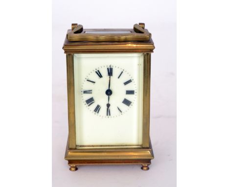 A 19th Century French brass carriage clock the enamelled dial and movement within a bevelled glass panelled case on cone feet