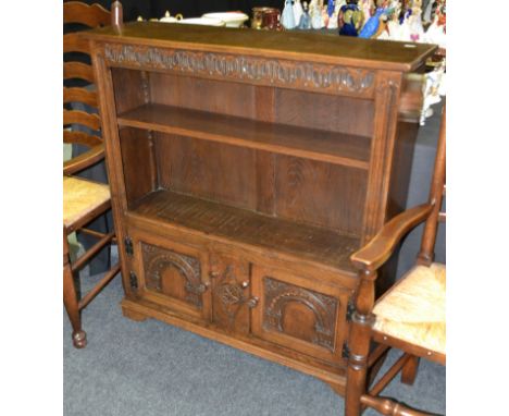 A 17th Century style oak open bookcase the adjustable shelf over a pair of arch panelled doors, width 96cm