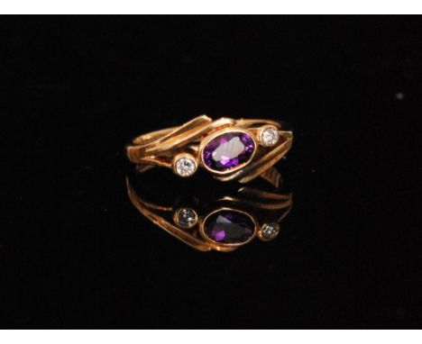 A 9ct hallmarked amethyst and diamond three stone ring, central oval collar set amethyst flanked by a diamond to either side,