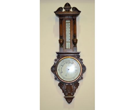 A 1930s carved oak aneroid barometer, circular dial below a thermometer, height 58cm