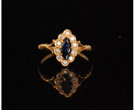 An 18ct hallmarked sapphire and diamond cluster ring, central claw set marquise sapphire within a ten stone diamond surround,