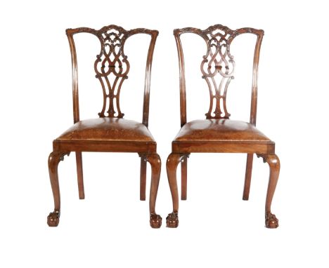A pair of Chippendale style carved mahogany dining chairs the undulating top rails over pierced vase splats above brown leath