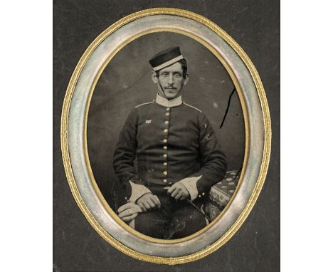 * Half-plate ambrotype of a soldier of the British Army, c.1860, three-quarter length and seated, wearing a pillbox hat, gilt