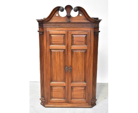 A mahogany wall-hanging flat-fronted corner cupboard, the broken swan neck pediment centred with a carved shell motif, above 