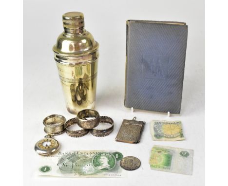 A group of four non-matching hallmarked silver napkin rings, a small coin, a white metal notebook with propelling pencil, Ger