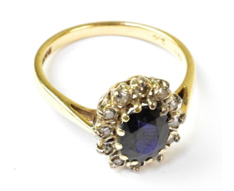 A 9ct gold sapphire and diamond ring, the central blue claw set sapphire within a halo of twelve small claw set diamonds, in 