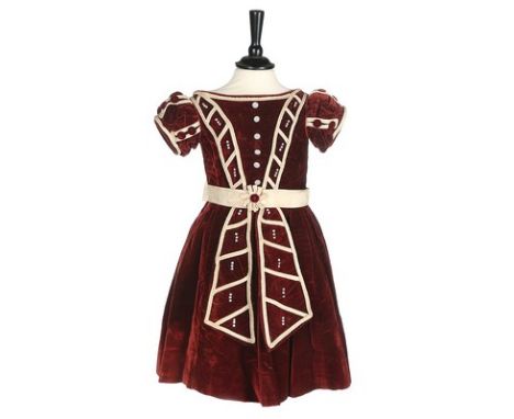 An unusual commemorative child's dress, 1863, of burgundy velvet with ivory satin piping, mother of pearl buttons, and taffet