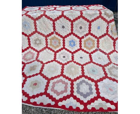 A 19thC patchwork quilt with hexagonal blocks on a red background, white to the reverse. Approx. 244 x 208cm.