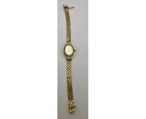 A ladies Bulova 14 carat gold wristwatch and bracelet with diamond encrusted bezel and sapphire cabochon winding crown. Lengt