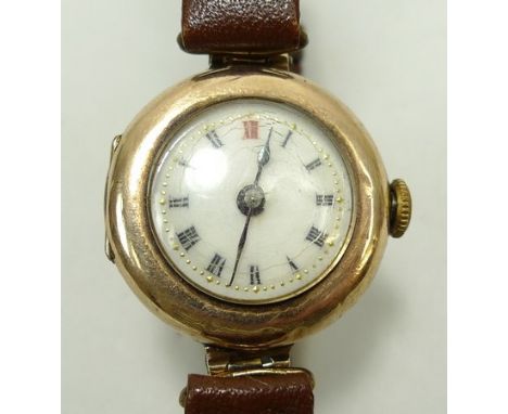 A 1920's 9ct gold circular cased lady's wristwatch with enamel dial bearing Roman numerals, on a leather strap, boxed. 
