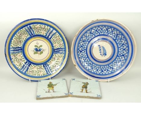 A pair of Delftware tiles, 19th century, polychrome decorated with huntsmen, 13 by 13cm, and two tin glazed earthenware dishe