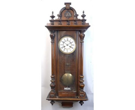 A Victorian walnut and ebonised wall clock, enamel dial bearing Roman numerals, movement with coil strike, 98cm long, with ke