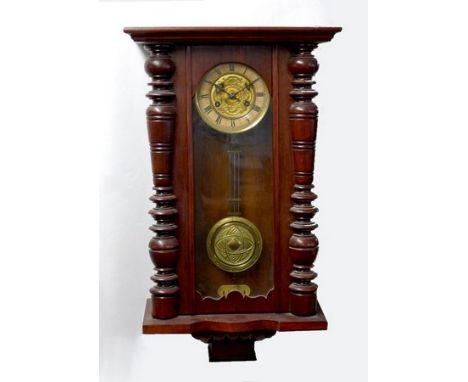 An early 20th century mahogany cased chiming Vienna wall clock with turned columns, brass and enamel face with Roman numerals