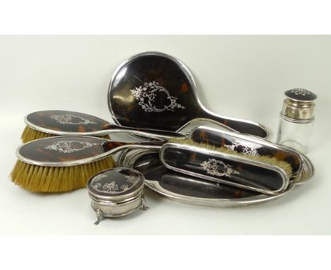 An Edwardian tortoiseshell and silver dressing table set, comprising two hair brushes, two clothes brushes, a mirror and a tr