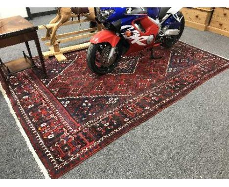 A fringed Persian Kashgai carpet on red ground 