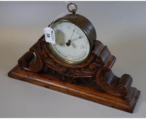 19th century brass drum shaped barometer with thermometer, unnamed, on a carved oak scrolled and foliate moulded stand. 12.5c