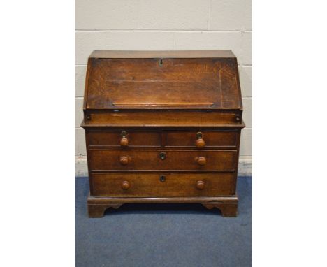 A GEORGIAN AND LATER OAK BUREAU, the fall front with a moulded bookrest, enclosing a fitted interior with various pigeon hole