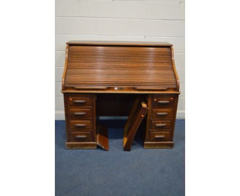 AN EARLY 20TH CENTURY OAK ROLL TOP DESK, with a fitted interior with an assortment of shelves and drawers, above a pair of fo