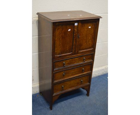 AN EARLY TO MID 20TH CENTURY SOLID OAK TWO DOOR CABINET, enclosing a sliding shelf, above three graduated drawers, width 65cm